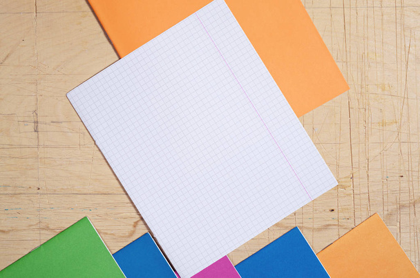 Top view on empty sheet and colored school notebooks on old wooden desk - Photo, Image