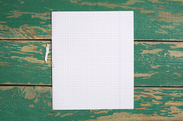 Leeg vel uit een notitieblok voor leerling op oude groene houten achtergrond, bovenaanzicht - Foto, afbeelding