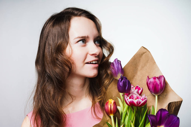 joyful girl with long hair keeps a bouquet of fragrant flowers, spring holidays - Foto, Imagem
