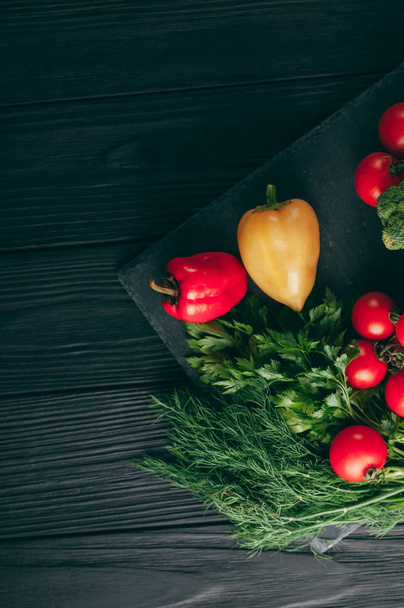 Fresh vegetables: cherry tomatoes, broccoli, pepper, dill, parsley on a dark wooden table. Recipe. Ingredients. Dietary food. Place under the text. View from above - 写真・画像