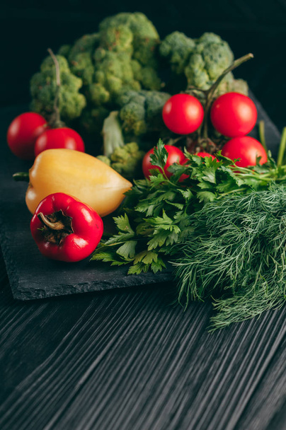 Légumes frais : tomates cerises, brocoli, poivre, aneth, persil sur une table en bois sombre. Recette. Ingrédients. Nourriture diététique. Placer sous le texte. Vue d'en haut
 - Photo, image