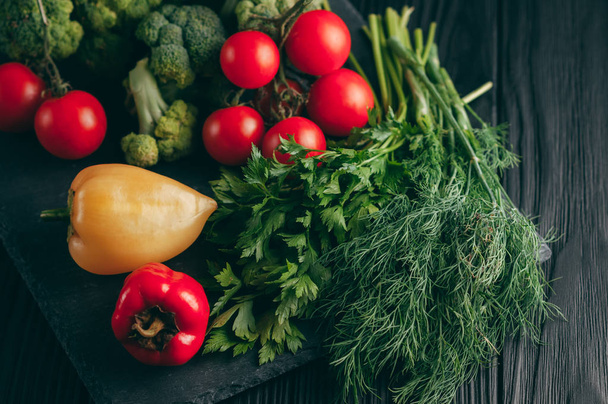 新鮮な野菜: チェリー トマト、ブロッコリー、コショウ、ディル、パセリ暗い木製のテーブル。レシピ。食材。ダイエット食品。テキストの下に置きます。上からの眺め - 写真・画像