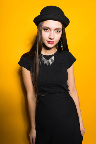 confident stylish girl in a black dress and hat posing, on the neck an expensive necklace - Foto, Imagen