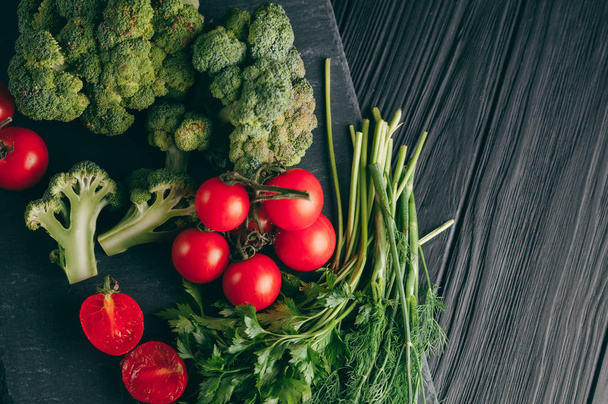 暗い木製のテーブル、新鮮な緑のブロッコリー、パセリ、ディル、チェリー トマト、健康のためにレシピ。食材。ダイエット食品。テキストの下に置きます。トップ ビュー - 写真・画像