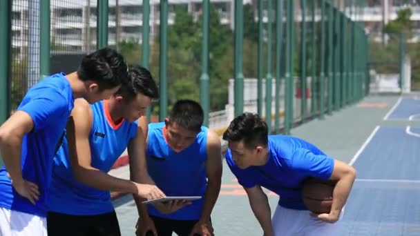Gruppe junger erwachsener asiatischer Basketballspieler diskutiert Taktik mit digitalem Tablet. - Filmmaterial, Video