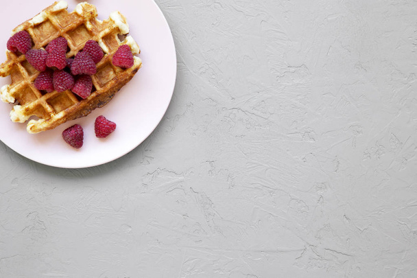 Традиционные бельгийские вафли с малиной на розовой тарелке на бетонном фоне, вид сверху. Копирование пространства
. - Фото, изображение