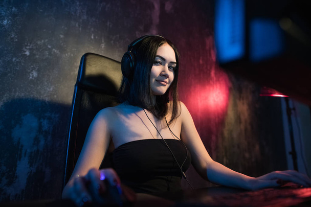 Girl gamer in headphones and with a computer mouse in her hand streaming playthrough or walkthrough video. - Photo, Image