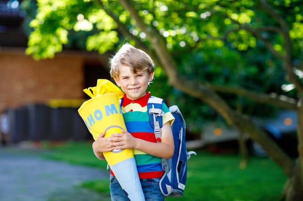 kis gyerek fiú iskola táska, iskola, iskola kúp ajándékokkal holding első napján - Fotó, kép