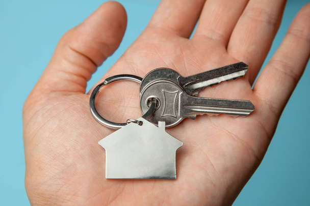 Ключи и брелок под рукой. Концепция покупки дома, сдачи в аренду
 - Фото, изображение