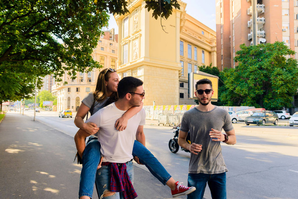 Ystävien ryhmä kävelee kadulla ja pitää hauskaa aurinkoisena päivänä
 - Valokuva, kuva
