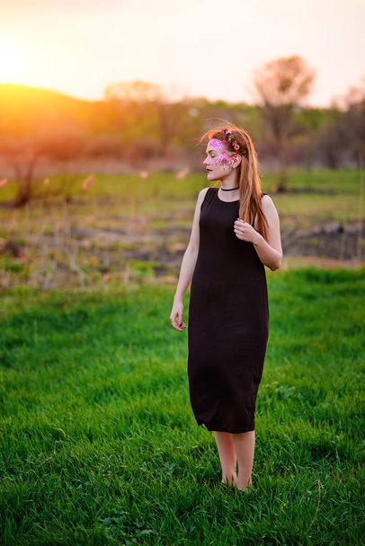 Mladá krásná žena s fialovým leskem na její tváři stojí na trávě. - Fotografie, Obrázek