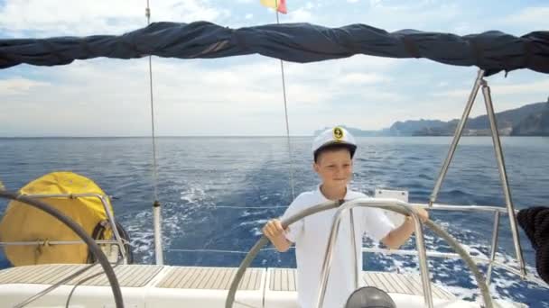 Litle bambini capitano al timone controlli di uno yacht a vela durante la gara
. - Filmati, video