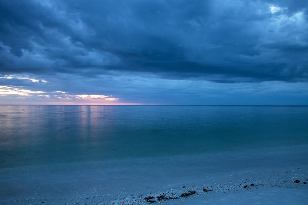 Regen giet van donkere wolken boven Clam Pass strand in Naples, Florida rond zonsondergang. - Foto, afbeelding