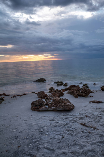 Regen giet van donkere wolken boven Clam Pass strand in Naples, Florida rond zonsondergang. - Foto, afbeelding