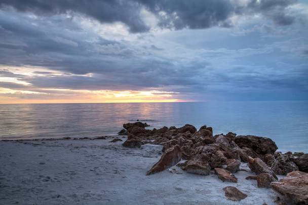 Rain pours from dark clouds over Clam Pass Beach in Naples, Florida around sunset. - Photo, Image