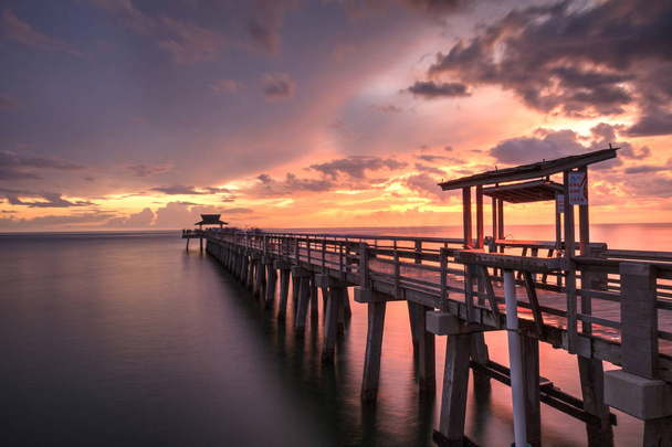 Pink and purple sunset over the Naples Pier on the Gulf Coast of - Photo, Image