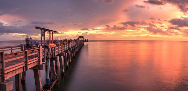Ροζ και μοβ ηλιοβασίλεμα πάνω από το Pier Νάπολη της Φλόριντα ακτή της Νάπολης κόλπο το καλοκαίρι. - Φωτογραφία, εικόνα