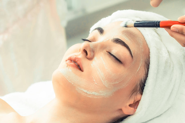 Mooie vrouw met een gezichtsverzorging cosmetische scrub behandeling van professionele dermatoloog bij wellness spa. Anti-aging, gezichtsverzorging en luxe lifestyle concept. - Foto, afbeelding