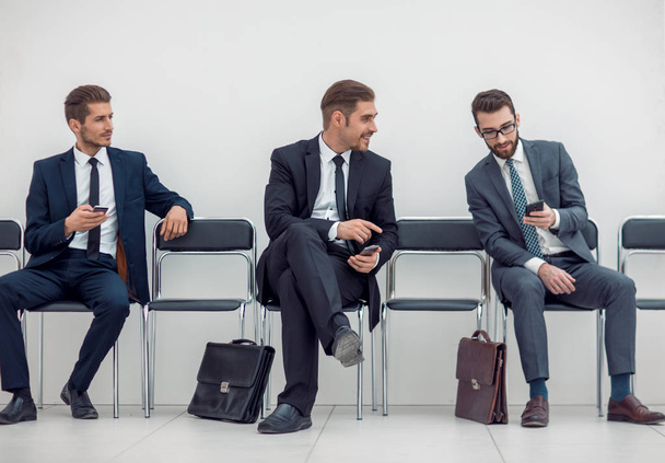 employees with smartphones sitting in the office hallway - Photo, Image