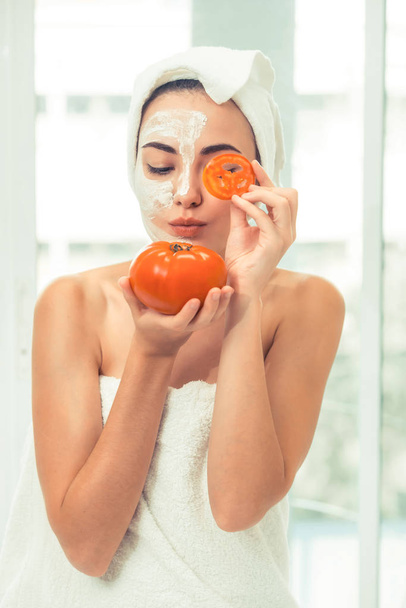 Mulher bonita ter um tratamento de máscara facial com extrato de creme de tomate mostrando benefício do tratamento da natureza. Cosmetologia anti-envelhecimento, cuidados com a pele facial e conceito de estilo de vida de luxo
. - Foto, Imagem