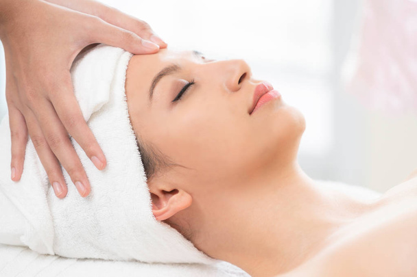 Pihent nő fekszik a spa ágy arc- és fejmasszázs spa kezelés masszázs terapeuta egy luxus spa üdülőhely. Wellness, stresszoldó és fiatalító koncepció. - Fotó, kép