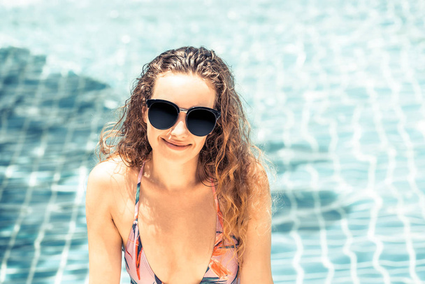 Onnellinen nuori nainen uimapuvussa, jolla on hauskaa uima-altaalla ylellisessä lomakeskuksessa. Kesä matka loma käsite
. - Valokuva, kuva