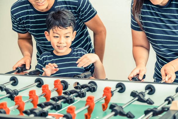 Happy kid playing foosball table soccer with family, father and mother. - Φωτογραφία, εικόνα