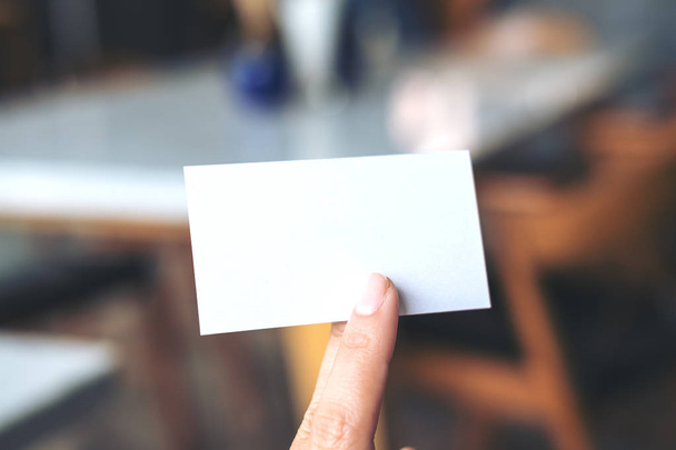 Una imagen de una mano sosteniendo la tarjeta de visita vacía en la cafetería moderna
 - Foto, Imagen