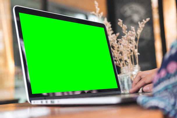 Makieta obrazu kobiety za pomocą laptopa z pustego ekranu zielony na drewnianym stole w biurze - Zdjęcie, obraz