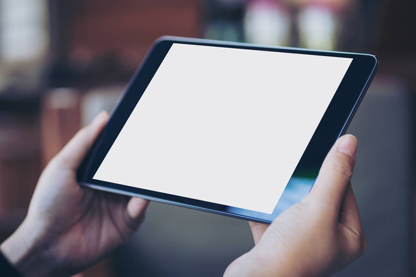 Imagen burlona de la mano de la mujer sosteniendo PC tableta negra con pantalla blanca en blanco en café de madera
 - Foto, imagen