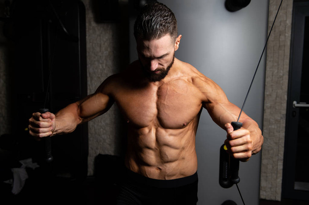 Construtor de musculação muscular bonito fazendo exercício de peso pesado para peito na máquina com cabo no ginásio - Foto, Imagem