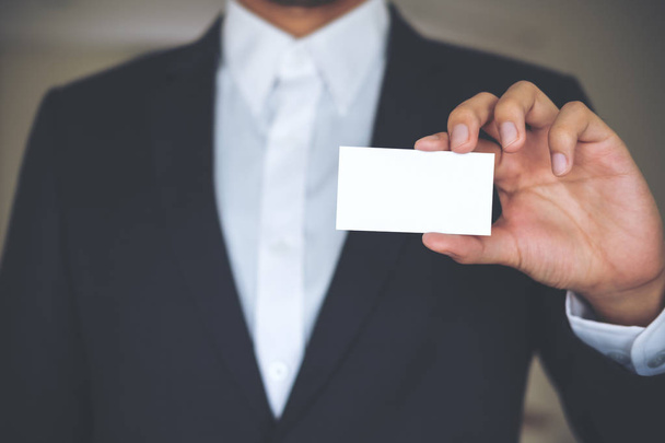 白いシャツとグレーのスーツを保持していると空のビジネス カードを示すビジネスの男性  - 写真・画像