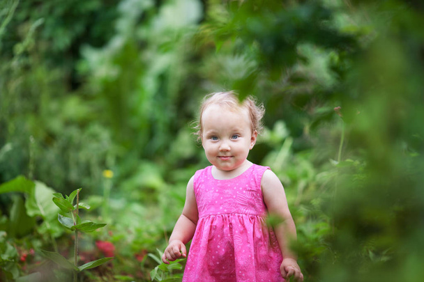 Portrait of cute little girl in summer garden on background of flowers - 写真・画像
