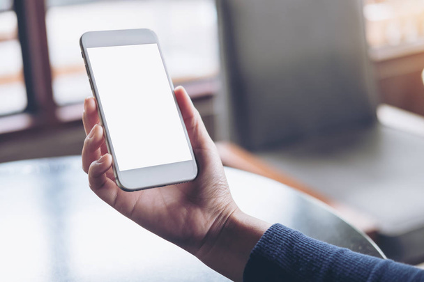 Изображение руки, держащей белый мобильный телефон с пустым экраном на столе в кафе
 - Фото, изображение