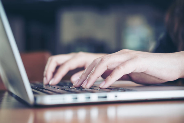 Imagem de close-up das mãos de uma mulher de negócios trabalhando e digitando no teclado do laptop na mesa de madeira no escritório
 - Foto, Imagem