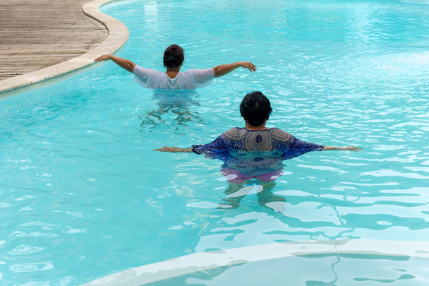 Dwóch starszych kobiet robi aqua aerobik ćwiczenia w basenie. - Zdjęcie, obraz