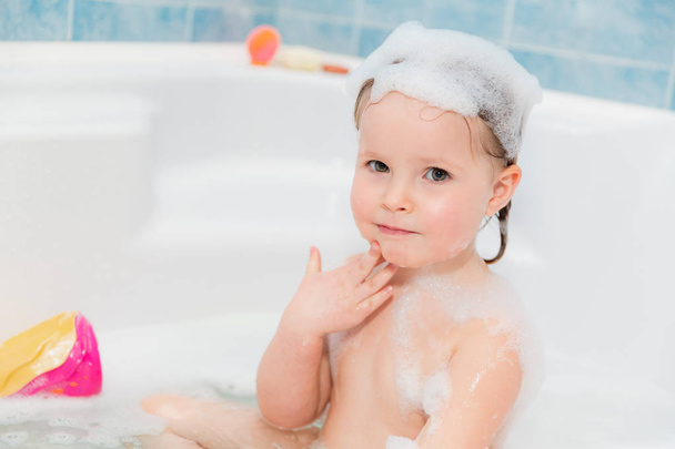 Kleines Mädchen wäscht sich in Badewanne mit Seife auf dem Kopf - Foto, Bild