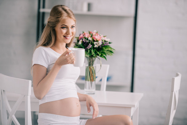 retrato de mujer embarazada feliz con taza de té en casa
 - Foto, imagen