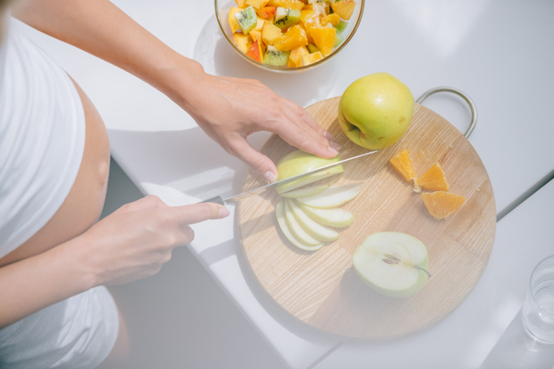 lövés a terhes nő levágott késsel gyümölcs saláta otthon főzés - Fotó, kép