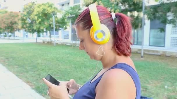     smiling woman walking listen music with headphone  - Filmati, video