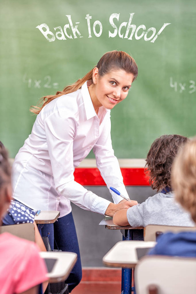 Female teacher happy in primary classroom, back to school sign on the chalkboard. - Φωτογραφία, εικόνα