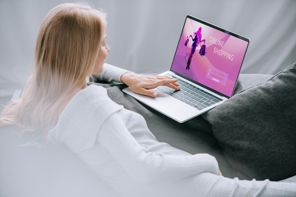 mujer embarazada usando el ordenador portátil con el cartel de compras en línea en la pantalla en el sofá en casa
 - Foto, Imagen