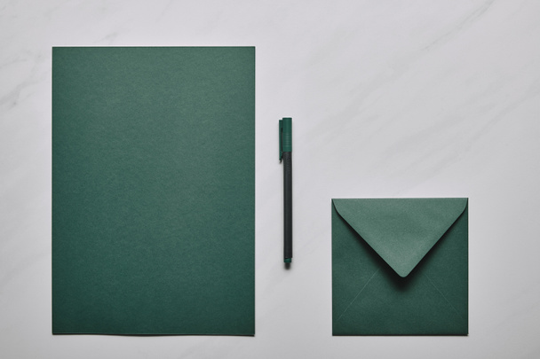 Green letter template with envelope and pen on white marble background - Fotoğraf, Görsel