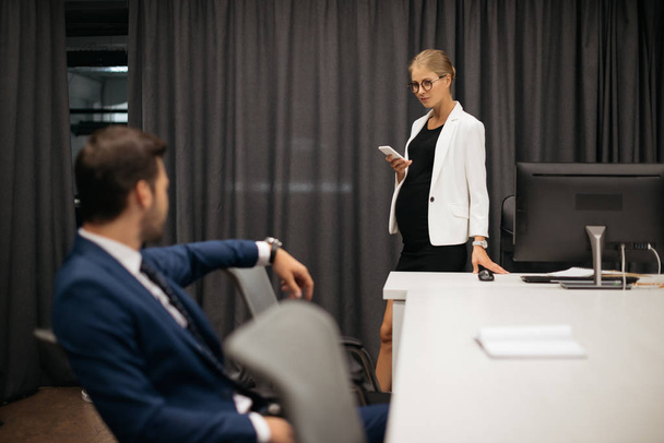 избирательный фокус деловой женщины со смартфоном и коллегой на рабочем месте в офисе
 - Фото, изображение