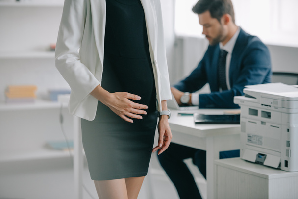 visión parcial de la mujer de negocios embarazada y colega en el lugar de trabajo en la oficina
 - Foto, imagen