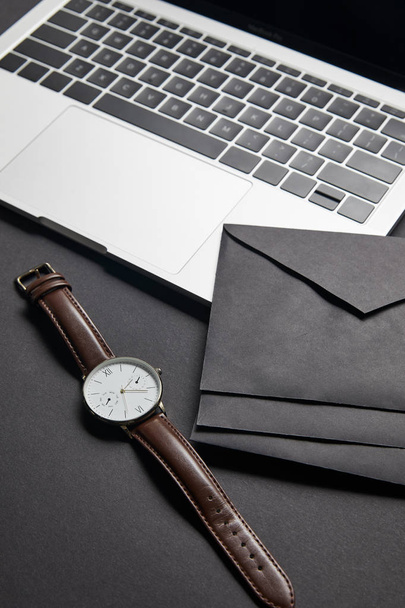 Black envelops and watch by laptop on black background - Photo, Image
