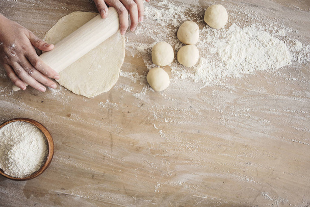 Female hands rolling dough on wooden table - Zdjęcie, obraz