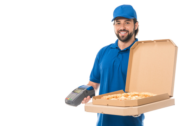schöner Lieferant mit Pizza in Schachteln und Zahlungsterminal, lächelt in die Kamera isoliert auf weiß    - Foto, Bild