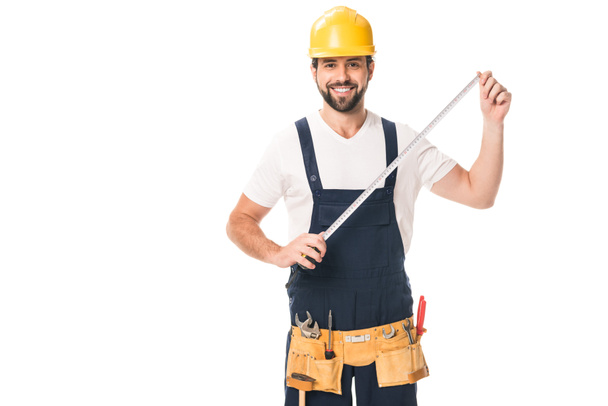 handsome happy workman holding measuring tape and smiling at camera isolated on white - Photo, Image