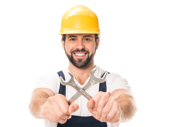 handsome repairman holding wrenches and smiling at camera isolated on white - Photo, Image